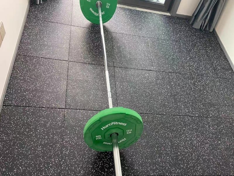 A stack of 1m x 1m black interlocking rubber gym tiles ready for installation.